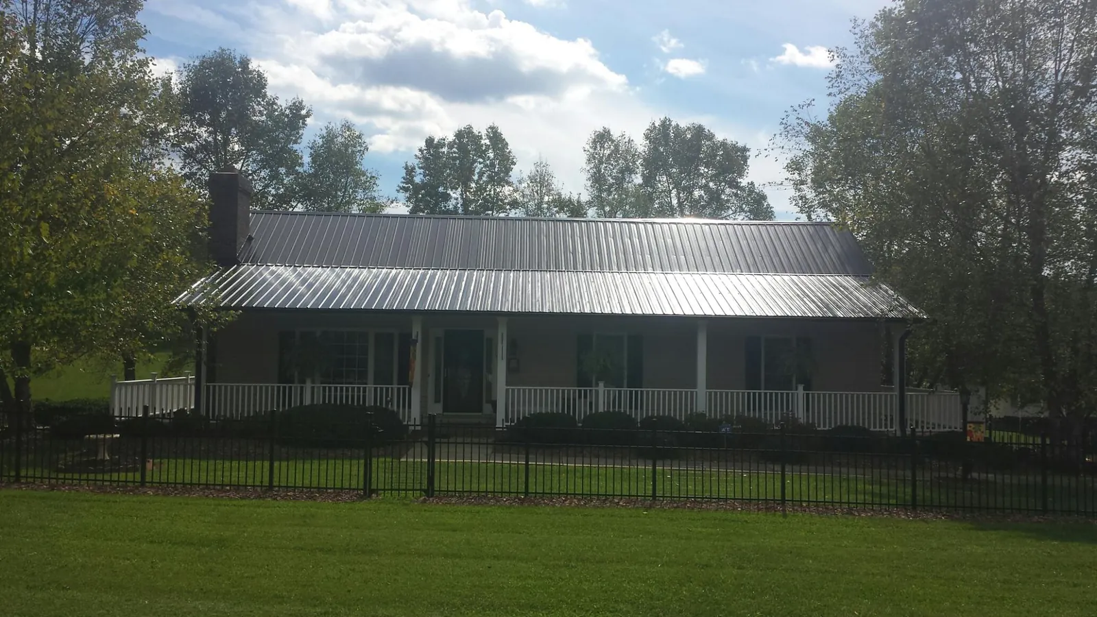 Gray metal roof on a brick ranch with a full width front porch — Gutter Guard Installation work by our crew in Hampshire