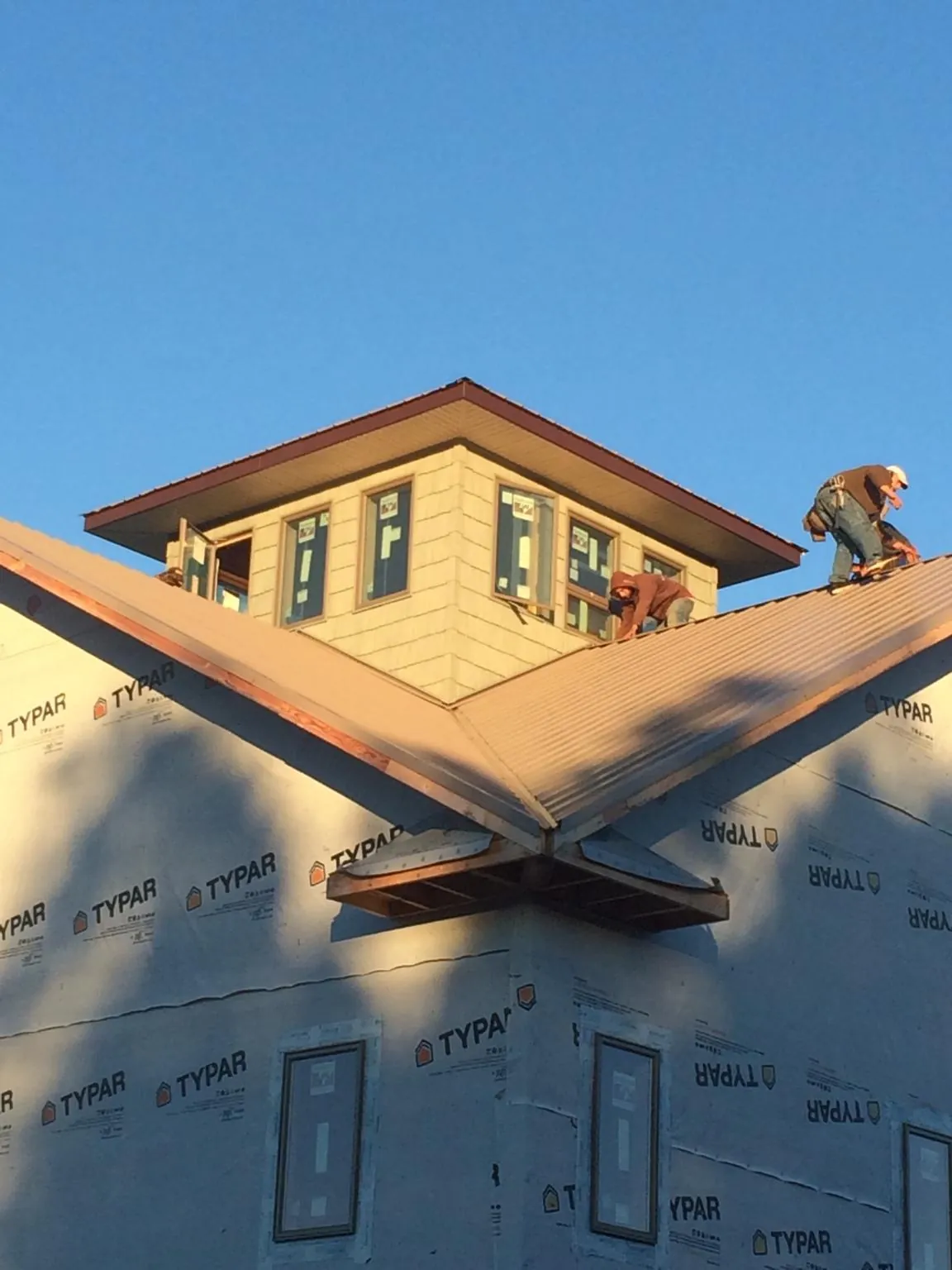 Roofers working around a rooftop cupola on a new metal roof at sunset — Roof Waterproofing in Hampshire by Roofing Brothers